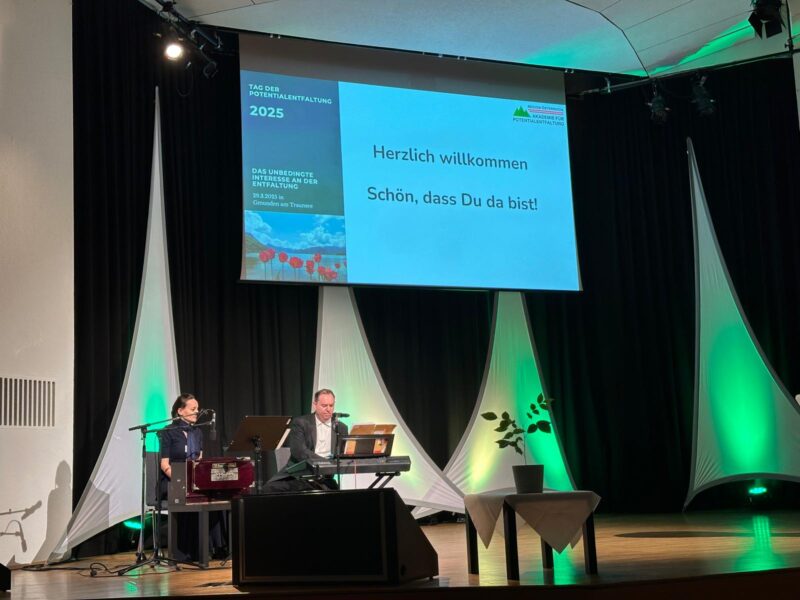 Emanuel und Elisabeth sitzen auf der Bühne beim Kongress der Potentialentfaltung in Gmunden. Emanuel spielt Keyboard und Elisabeth spielt Harmonium
